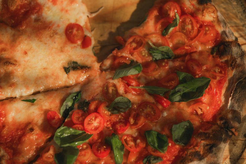 Top view of a baked Margherita pizza with cherry tomatoes, mozzarella, and basil leaves. - Photo by Valentin Angel Fernandez on Pexels