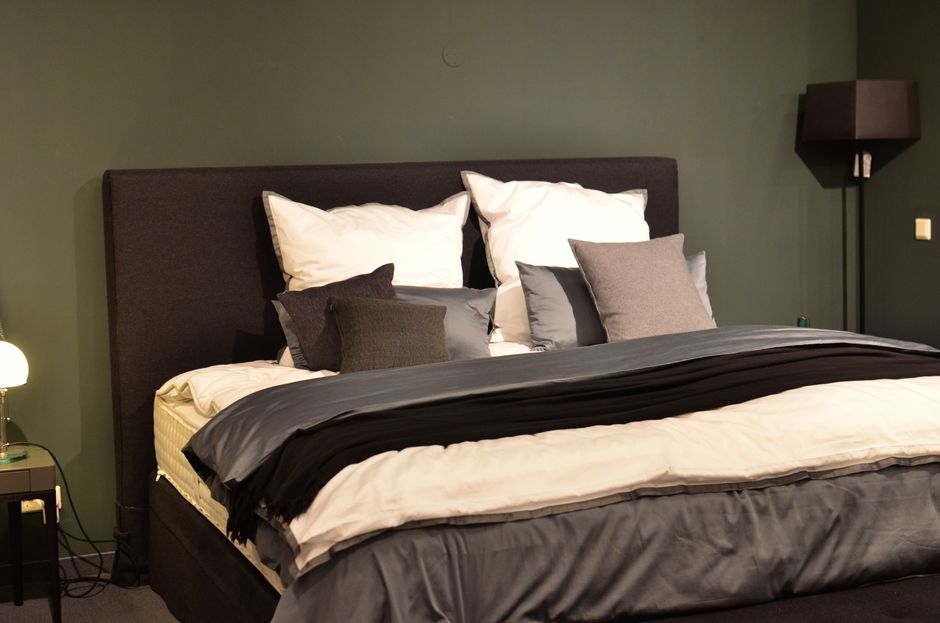 Creative design of bed with collection of cushions and cover between lamps in house - Photo by Skylar Kang on Pexels